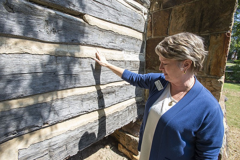 Angie Albright, director of the Shiloh Museum of Ozark History in Springdale points out deteriorating chinking  Tuesday Sept. 27, 2022 at the Ritter-McDonald Log Cabin on the museum grounds. The cabin was built in the 1850s at Elm Springs. The museum board is looking to preserve the condition of the log cabin on its grounds. For information about the museum see https://shilohmuseum.org/   Visit nwaonline.com/220928Daily/ for today's photo gallery.  (NWA Democrat-Gazette/J.T. Wampler)
