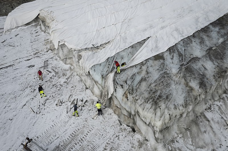 People work on a tarpaulin which cover the ice of the Corvatsch glacier on Monday, Sept. 5, 2022, near Samedan, Switzerland. Glaciologists have stopped their program to measure the glacier. The decision has already been taken in 2019 and the hot summer of 2022 has led to "extreme losses of ice" and the end of the program. The covered part of the glacier is used as a ski slope in winter. (Gian Ehrenzeller/Keystone via AP,file)