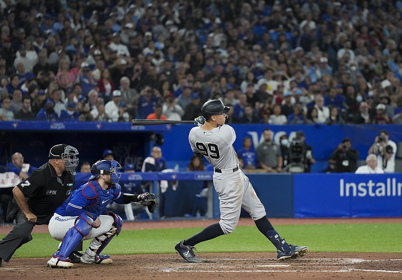 New York Yankees'Aaron Judge (99) follows through on his 61st home run of the season, next to Toronto Blue Jays catcher Danny Jansen during the seventh inning of a baseball game Wednesday, Sept. 28, 2022, in Toronto. (Nathan Denette/The Canadian Press via AP)