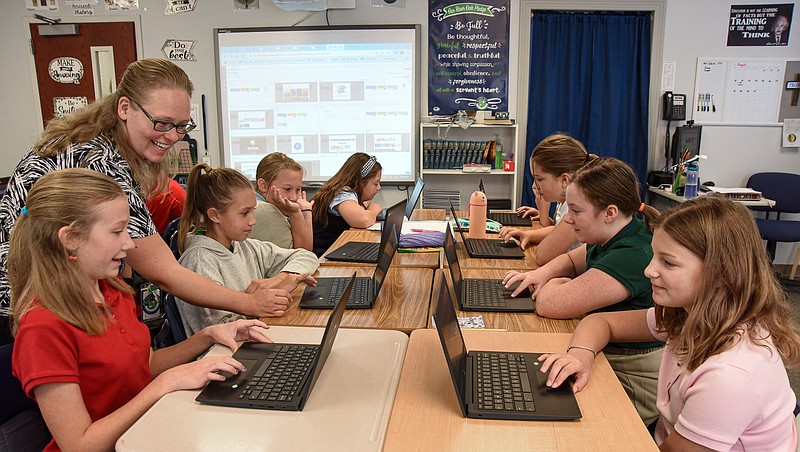 Julie Smith/News Tribune
Michelle McCune assists 6th-grade students at River Oak Christian Academy set up their individual Chromebook as the second day of a new school year gets underway in August. Seated at the table clockwise are: Kerstyn LePage, Alaina Sellers, Ellie Schwartz, Sophia Davidson, Ellia Brady, Lizzie Alvin, Vada Jarvis and Rachel Kremer.