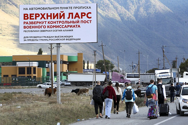 People walk toward the border crossing at Verkhny Lars between Georgia, bottom, and Russia leaving Chmi, North Ossetia–Alania Republic, Russia, Wednesday, Sept. 28, 2022. Long lines of vehicles have formed at a border crossing between Russia's North Ossetia region and Georgia after Moscow announced a partial military mobilization. A day after President Vladimir Putin ordered a partial mobilization to bolster his troops in Ukraine, many Russians are leaving their homes. (AP Photo)