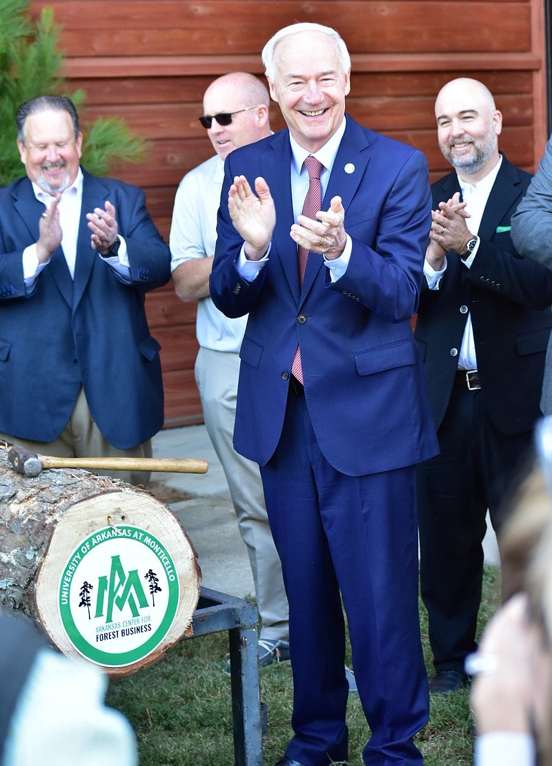Arkansas Gov. Asa Hutchinson and others applaud the ceremonial log breaking to signify the establishment of the Arkansas Center for Forest Business at the University of Arkansas at Monticello on Thursday. (Pine Bluff Commercial/I.C. Murrell)