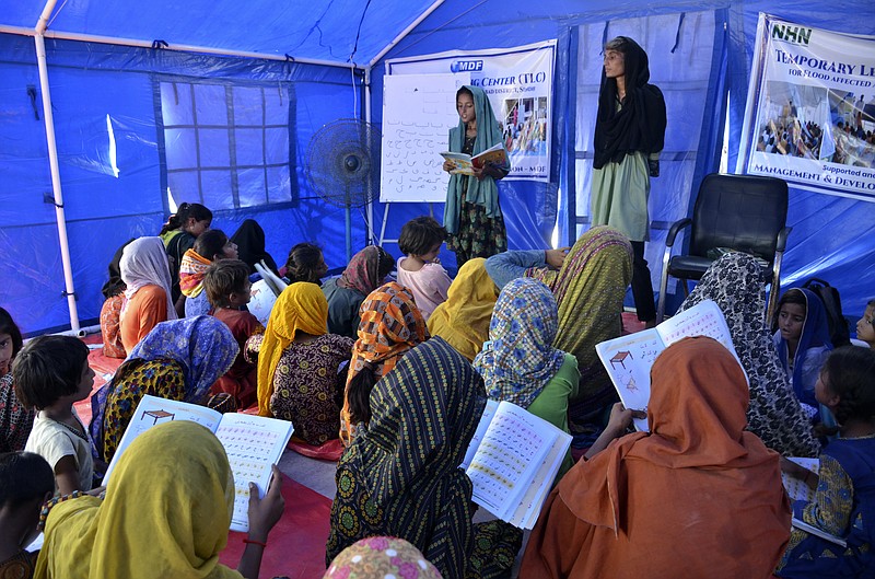 Victims of heavy flooding from monsoon rains attend school at a flood relief camp in Hyderabad, Pakistan, Saturday, Sept. 10, 2022. Months of heavy monsoon rains and flooding have killed over a 1000 people and affected 3.3 million in this South Asian nation while half a million people have become homeless. (AP Photo/Pervez Masih)