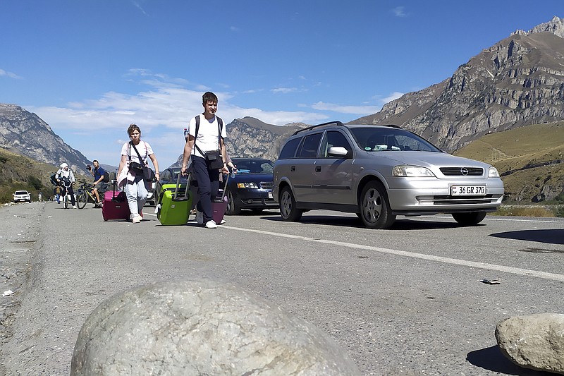 People cross into Georgia from Russia on Thursday, Sept. 29, 2022, at the Verkhny Lars crossing. Long lines of vehicles have formed at a border crossing between Russia's North Ossetia region and Georgia after Moscow announced a partial military mobilization. A day after President Vladimir Putin ordered a partial mobilization to bolster his troops in Ukraine, many Russians are leaving their homes. (AP Photo)