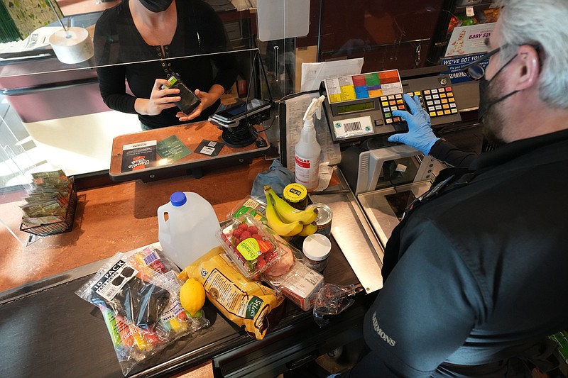 A cashier assists a customer at a checkout counter Oct. 21, 2021, at Harmons Grocery store in Salt Lake Cit (Bloomberg photo by George Frey)