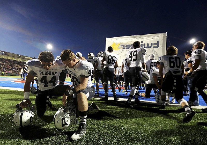 Permian linebacker Israel Martinez, left, and defensive lineman Tyler Tomlinson pray before a high school football game against Abilene on Friday, Oct. 17, 2014, at Shotwell Stadium in Abilene, Texas. Abilene won, 30-13. A poll by The Associated Press and the NORC Center for Public Affairs Research conducted Sept. 9-12, 2022, finds that about 3 in 10 Americans say they feel God plays a role in determining which team goes home the victor. (Edyta Blaszczyk/Odessa American via AP, File)