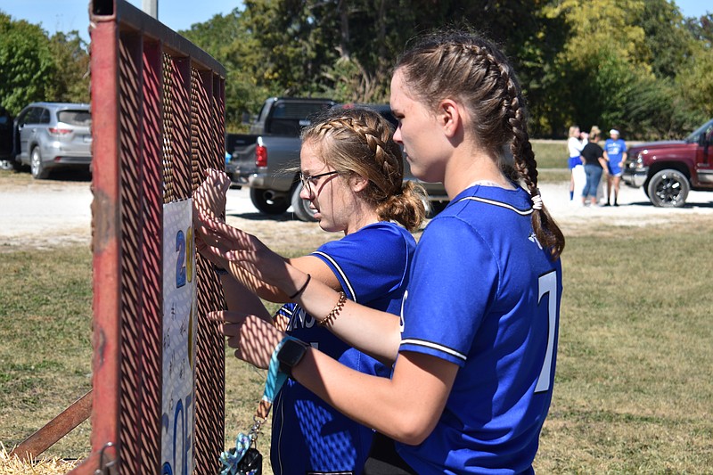 Democrat photo/Garrett Fuller — Freshman Karleigh Grayson, left, and Kylee Scheperle, sophomore, fasten a banner to the back of the Russellville Indians softball float Friday (Sept. 30, 2022,) before the Russellville Homecoming Parade in the high school parking lot.