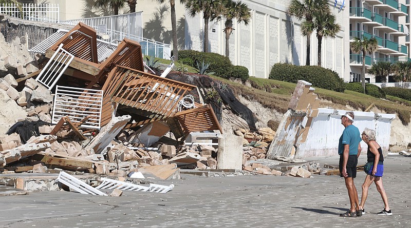 Beachgoers survey the damage Monday, Oct. 3, 2022, in Daytona Beach Shores, Fla., as hotel and condo seawalls and pool decks along the Volusia County coastline were gutted by Hurricane Ian last week. (Joe Burbank/Orlando Sentinel via AP)