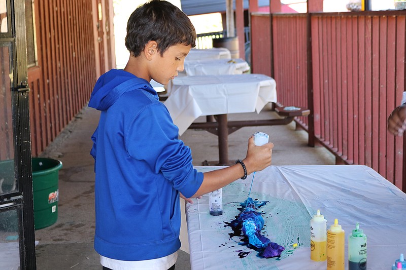 Anna Campbell/News Tribune photo: 
Malachi Martin adds dye to his tie-dyed shirt Tuesday, Oct. 4, 2022, at South Elementary's Outdoor Education Day at Binder Park.