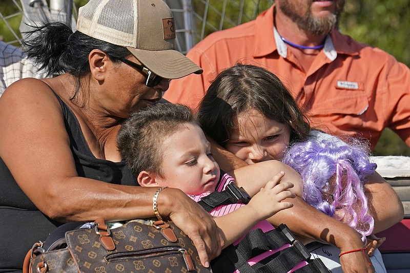 FILE - Yolanda Rios, left, holds her grandchildren Ava, 7, and Giovanni, 5, as as they are evacuated by airboat through floodwaters along the Peace River, to get to a hospital for medical care, in the aftermath of Hurricane Ian on Arcadia, Fla., Monday, Oct. 3, 2022. The devastation from Hurricane Ian has left schools shuttered indefinitely in parts of Florida, leaving storm-weary families anxious for word on when and how children can get back to classrooms. (AP Photo/Gerald Herbert, File)