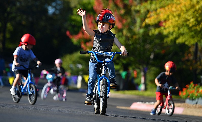 Boone Landry Kuester, 5, waves to his mother Thursday while riding his bicycle with other students during the annual First School Trike Rally at First United Presbyterian Church in Fayetteville. The school hosts the rally in conjunction with Bikes, Blues & BBQ in order to teach bike safety, have fun and raise money for St. Jude Children’s Research Hospital in memory of a former student who died of cancer. Visit nwaonline.com/221007Daily/ for today’s photo gallery.

(NWA Democrat-Gazette/Andy Shupe)