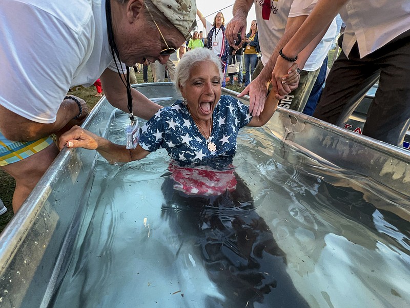 A woman is baptized during the ReAwaken America Tour at Cornerstone Church on Friday, Aug. 12, 2022, in Batavia, N.Y. In the version of America laid out at the ReAwaken tour, Christianity is at the center of American life and institutions, it's under attack, and attendees need to fight to restore and protect the nation's Christian roots. It’s a message repeated over and over at ReAwaken — one that upends the constitutional ideal of a pluralist democracy. (AP Photo/Carolyn Kaster)