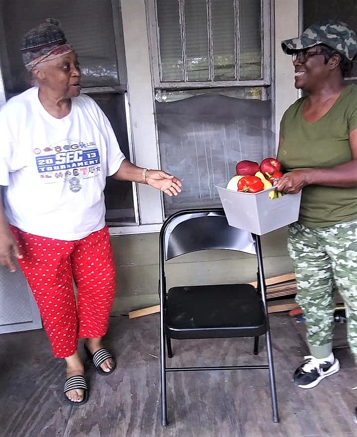 Veronica Bailey, left, founder and CEO of Meet Me at the Court, presents a "Love Basket" to St. Louis neighborhood resident Clara Scott. MMC Youth distributed the baskets throughout El Dorado and Union County as a part of the group's monthly mission project in August. The baskets were filled with fresh fruits, vegetables and "lots of love." (Contributed)
