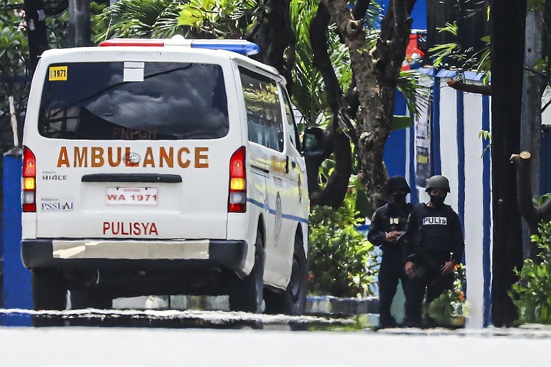 Police keep watch as an ambulance is parked outside the PNP Custodial Compound in Camp Crame police headquarters, Metro Manila, Philippines on Sunday Oct. 9, 2022. Philippine police killed three inmates, including a top Abu Sayyaf militant, after they stabbed a jail officer and briefly held detained former opposition Sen. Leila de Lima on Sunday in a failed attempt to escape from the police headquarters in the capital region, police said. (AP Photo/Gerard Carreon)