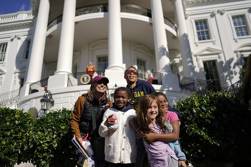 Lauren Serpe, back left, and Rashida Holman-Jones pose for photos with their kids from left, Zynn Jones, Sydney Serpe, and Zuri Jones, during the White House Fall Garden Tour on Saturday, Oct. 8, 2022, in Washington. (AP Photo/Carolyn Kaster)