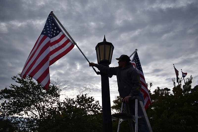 Democrat photo/Garrett Fuller — Rhett Kiesling, a parks department employee, is seen replacing an American flag Wednesday (Oct. 5, 2022,) on South Oak Street in front of the California City Hall.
