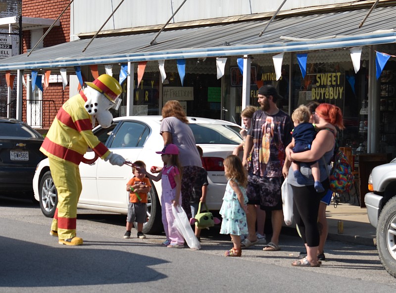 Democrat photo/Garrett Fuller — Sparky the Fire Dog, a mascot designed to help children learn about fire prevention, hands out candy Sept. 17, 2022, during the Ozark Ham & Turkey Festival in California.