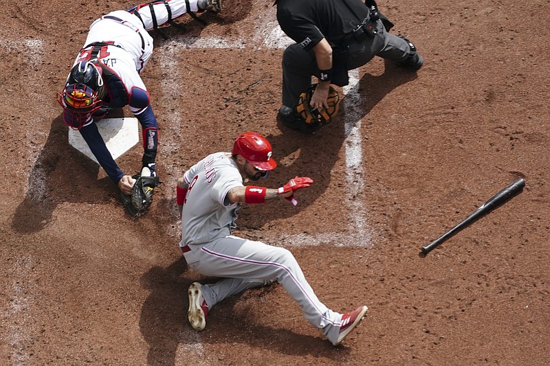 Philadelphia Phillies right fielder Nick Castellanos (8) scores against Atlanta Braves catcher Travis d'Arnaud (16) during the third inning in Game 1 of a National League Division Series baseball game, Tuesday, Oct. 11, 2022, in Atlanta. (AP Photo/John Bazemore)