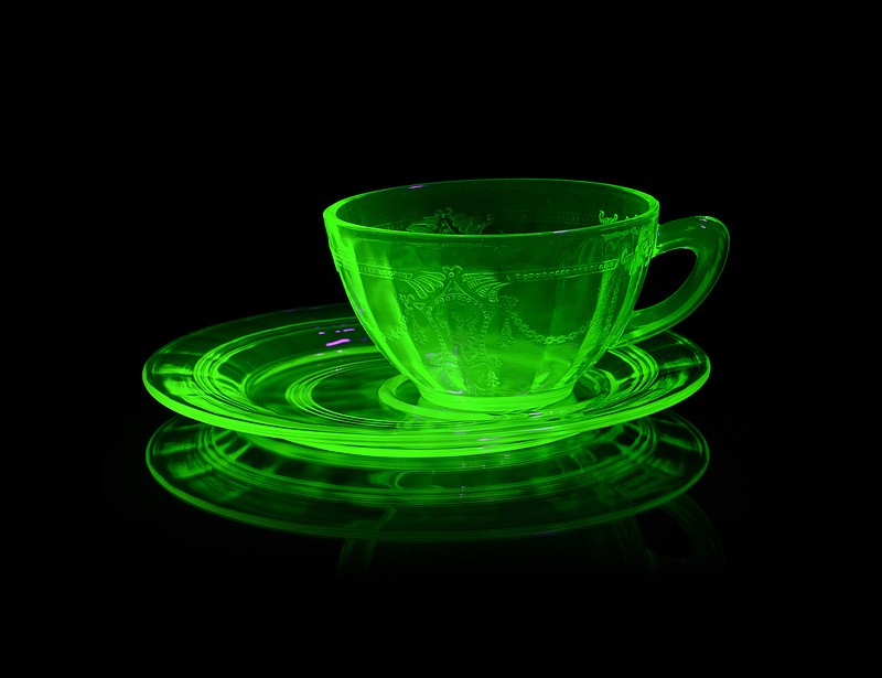 A glowing Uranium Glass Teacup and Saucer under Ultraviolet light to reveal its unique properties. 
(iStock/matt_benoiti)