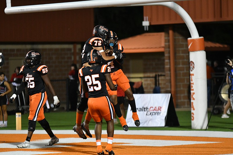 Photo by Kevin Sutton
Texas High's Javori Johnson (4) jumps into the air after scoring a touchdown while teammmate John Jack (72) gives him a hug. Joe Miller (25) and Evan Holeman (55) are also pictured in the play at Tiger Stadium in Grim Park.