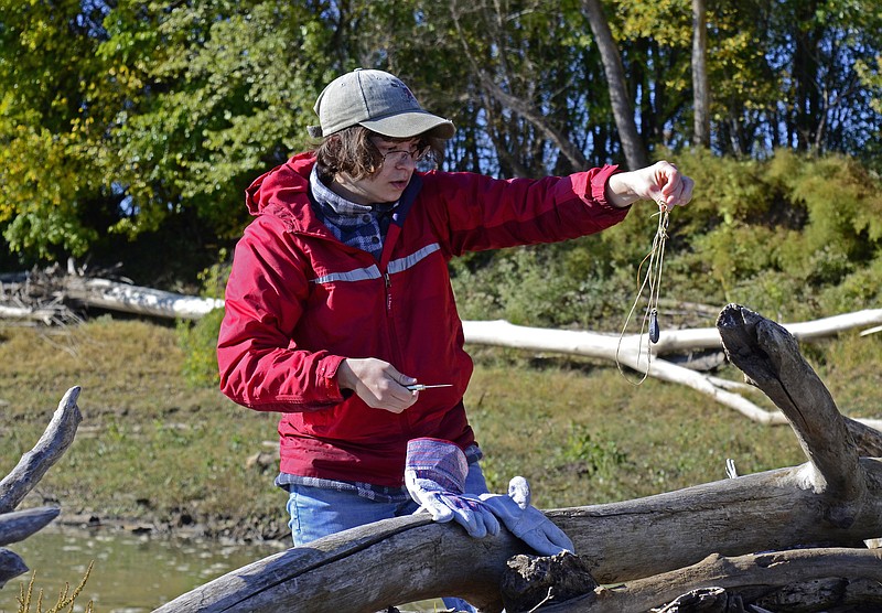 Eileen Wisniowicz/News Tribune photo:
Hollie Burrows picks up a piece of trash on Saturday, Oct. 15, 2022, at the Missouri River in Jefferson City. Burrows had to cut out the piece of rope that was stuck in driftwood.