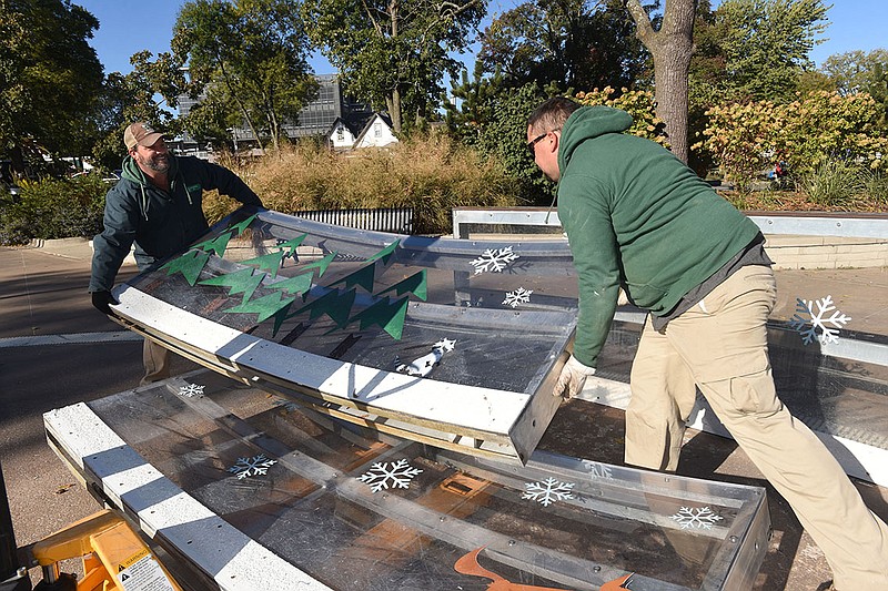 Will Snyder (left) and Nick Pilgrim, both with the Bentonville Parks and Recreation Department, unload panels Wednesday while putting together the ice skating rink at Lawrence Plaza in downtown Bentonville. The rink will open for skating Nov. 19, the same day as the annual lighting of the square celebration, the crew said. Go to nwaonline.com/221020Daily/ to see more photos.
(NWA Democrat-Gazette/Flip Putthoff)