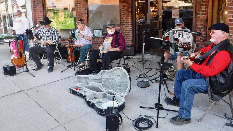Westside Eagle Observer/SUSAN HOLLAND Members of the Old Town String Band entertain the crowd at this month’s third Thursday event. Band members set up in front of the Chamber of Commerce office and played and sang several tunes. Pictured are Randy Cannon, Linda Damron, Jeff Davis, Marty Mullen and Al Blair. Sue Rice is seen in the background at left selling pecans to benefit the Lions Club.