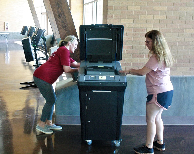 Early voting captains Heather DeBlieux and Amanda Kent set up the vote tabulator Sunday at the El Dorado Municipal Auditorium while preparing for the start of early voting. (Matt Hutcheson/News-Times)