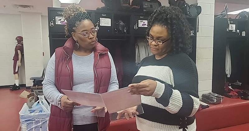 Zebra moms Trammell Howell and Daisha Thompson look at photos given to seniors in their gift bags provided by the Zebras' "Mom Squad." (Pine Bluff Commercial/Suzi Parker)