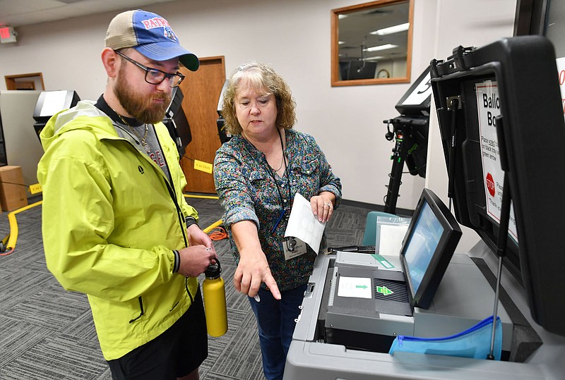 Ian Colwell (left) prepares to deposit his ballot Monday, Oct. 24, 2022, as election worker Jeanie Lee offers assistance with the machine after Colwell voted in the Washington County Courthouse in Fayetteville. Early voting began Monday and continues through Nov. 7 ahead of Election Day for the general election Nov. 8. Registered voters can cast ballots between 8 a.m. and 6 p.m. Monday through Friday and 10 a.m. to 4 p.m. on Saturdays, with some times varrying by location. Visit nwaonline.com/221025Daily/ for today's photo gallery. 
(NWA Democrat-Gazette/Andy Shupe)