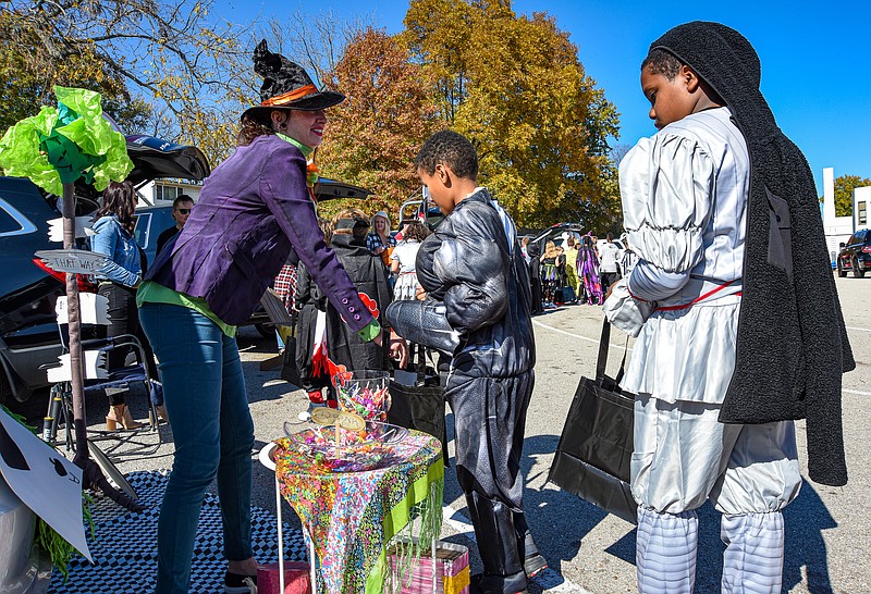 Julie Smith/News Tribune
A costumed Magen Sebastian hands candy to Chayse Abbott, middle, and Aaron Robinson, both of who are fifth graders at West School. Parents wore costumes and decorated their vehicles to hand out candy and trunk or treat on the school parking lot.