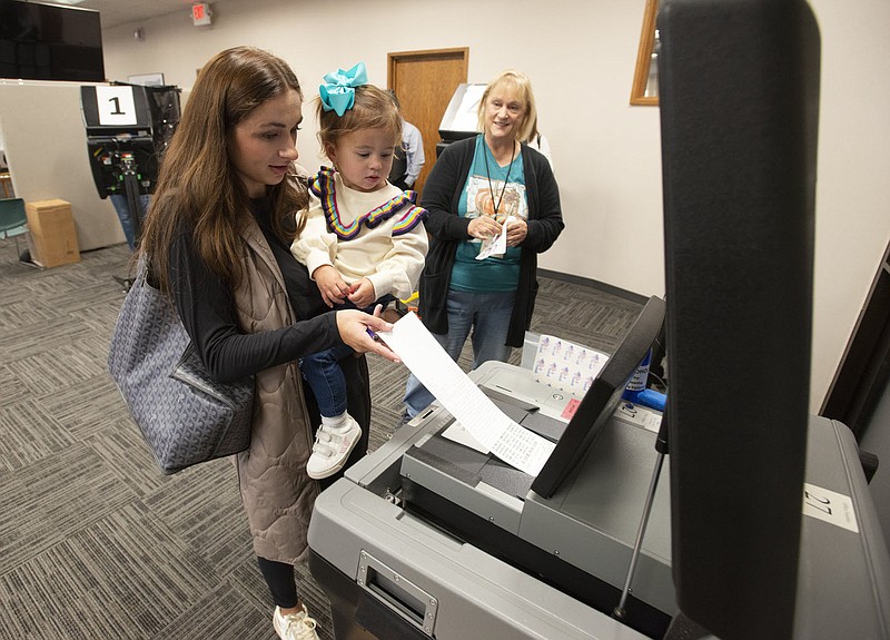 Bailey Tahy of Fayetteville holds her daughter Stella, 2, as she casts her ballot Friday while voting early at the Washington County Courthouse in Fayetteville. Election supervisor Sarah Harrison (right) was on hand to help voters. Visit nwaonline.com/221029Daily/ for today's photo gallery.
(NWA Democrat-Gazette/J.T. Wampler)