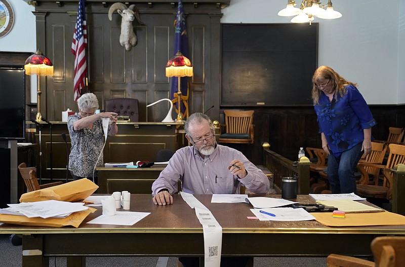 Esmeralda County Commissioner Ralph Keyes, center, works on a hand recount of votes with others, June 24, 2022, in Goldfield, Nevada. An AP survey shows the majority of candidates running this year for the state posts that oversee elections oppose the idea of hand counting ballots, a laborious and error-prone process that has gained favor among Republicans who have been inundated with unfounded voting machine conspiracy theories.  (AP Photo/John Locher, File)