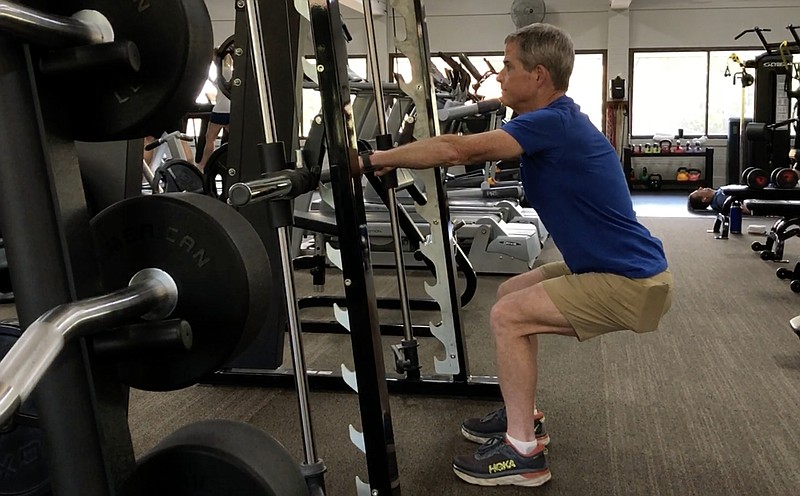 Jay Lloyd, a certified spin instructor and personal trainer at Little Rock Athletic Club, demonstrates the Bar Assisted Squat using a Smith machine at Little Rock Racquet Club. (Arkansas Democrat-Gazette/Celia Storey)