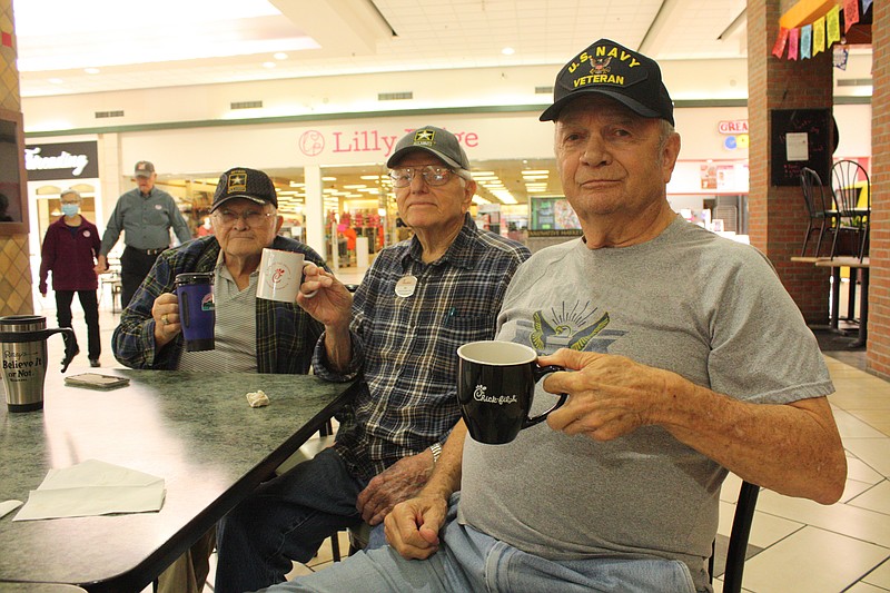 From right, Steve Woodruff, Bill Wilkins and James Hubbard hold the mugs they brought from home for their Chick-fil-A coffee fix on Monday, Oct. 31, 2022, at Central Mall in Texarkana, Texas. The veterans are a mall staple on Mondays, Wednesdays and Fridays, where they sit at their table for hours and talk about whatever comes to mind. (Staff photo by Mallory Wyatt)