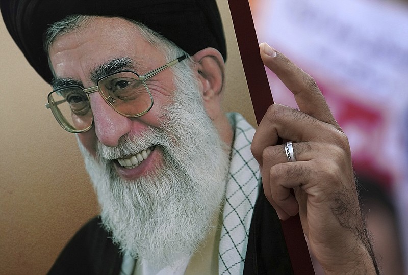 A man holds up a poster of Iranian Supreme Leader Ayatollah Ali Khamenei during a demonstration in front of the former U.S. Embassy in Tehran, Iran, Friday, Nov. 4, 2022. Iran on Friday marked the 1979 takeover of the U.S. Embassy in Tehran as its theocracy faces nationwide protests after the death of a 22-year-old woman earlier arrested by the country's morality police. (AP Photo/Vahid Salemi)