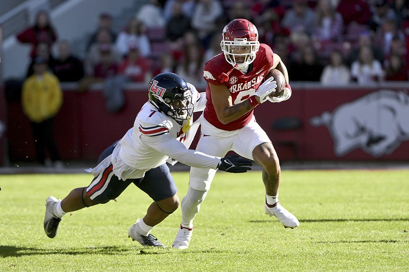 Arkansas wide receiver Jadon Haselwood, right, is tackled by Liberty linebacker Mike Smith Jr. (7) during the first half Saturday in Fayetteville. - Photo by Michael Woods of The Associated Press