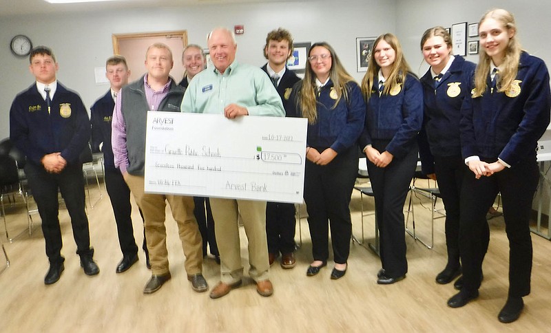 Westside Eagle Observer/SUSAN HOLLAND
Jim Singleton, president of Arvest Bank, displays a donation check presented to members of the Gravette FFA at the Oct. 17 meeting of the Gravette School Board. The $17,500 donation will be used to help fund the FFA trip to the national convention in Louisville, Kentucky. Pictured with Singleton are Clayton Nall (left), Jacob Mayo, agriculture teacher Justin Malott, Kassi Bird, Dakota Crawford, Hailey Harris, Autumn Fisher, Perri Miller, and Ashlyn Fox.
