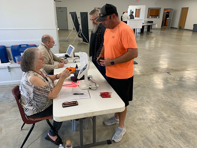 Lance Tucker checks in to vote with the help from poll worker Martha Newell in West Fork