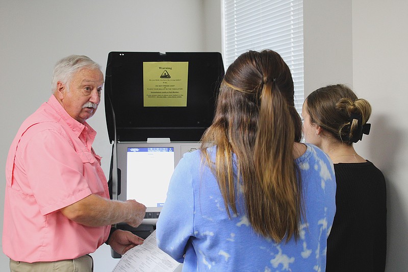 Republican election commissioner Mike Hayes, left, demonstrates to Makayla Harbour, center, and Katelyn Scott, right, how to select the correct ballot on one of the county's voting machines. Harbour and Scott spent Tuesday afternoon entering in absentee voters' ballots after a printing error prevented the original ballots from being counted. (Caitlan Butler/News-Times)