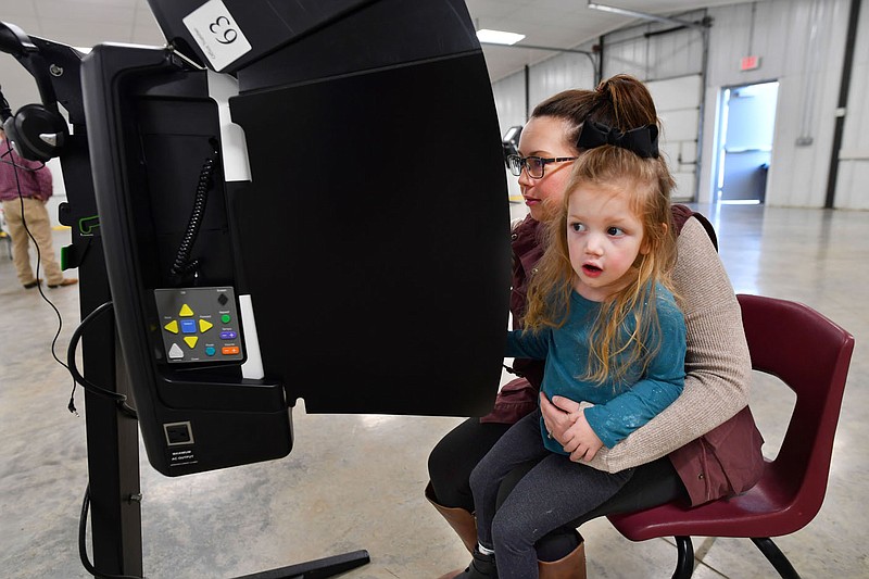 Remi Coker, 3, watches for her father Tuesday, Nov. 8, 2022, while sitting on the lap of her mother, Kaylee Coker, as she votes at the community center in West Fork. Visit nwaonline.com/221109Daily/ for today's photo gallery. 
(NWA Democrat-Gazette/Andy Shupe)