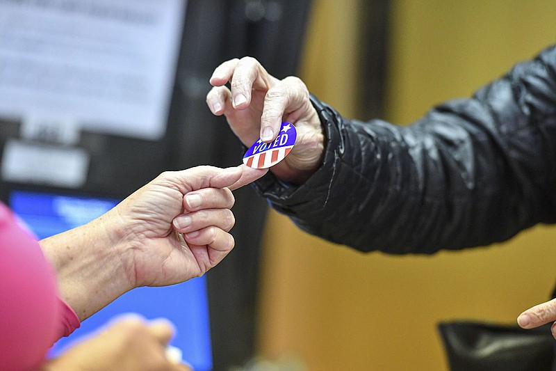 Jean Ann Sadler (left), a poll worker, distributes an “I voted” sticker to a voter Tuesday at the Creekmore Park Community Center in Fort Smith.
(NWA Democrat-Gazette/Hank Layton)