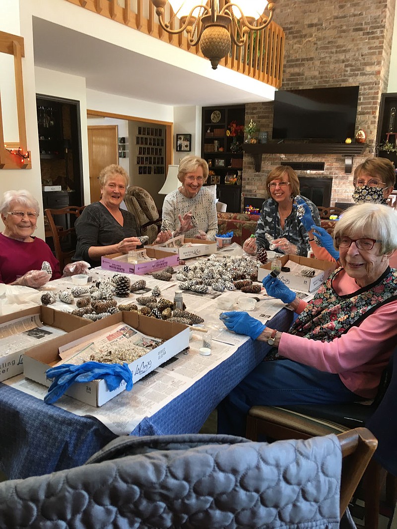 Photo submitted Several members of the Bella Vista Chapter of P.E.O. International meet in Nov. 2021 to start decorating pine cones that will be part of numerous swags the group is creating. Members will sell the swags for $15 as a holiday fundraiser. To order, email carebutler@aol.com.