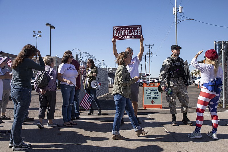 Republican supporters stand outside the Maricopa County Recorder's Office to protest what they allege is an unfair election in Phoenix, Saturday, Nov. 12, 2022.  Democratic Sen. Mark Kelly urged Arizonans to let go of “conspiracies of the past” on Saturday, calling for unity a day after he won re-election to a crucial Senate seat.  (AP Photo/Alberto Mariani)