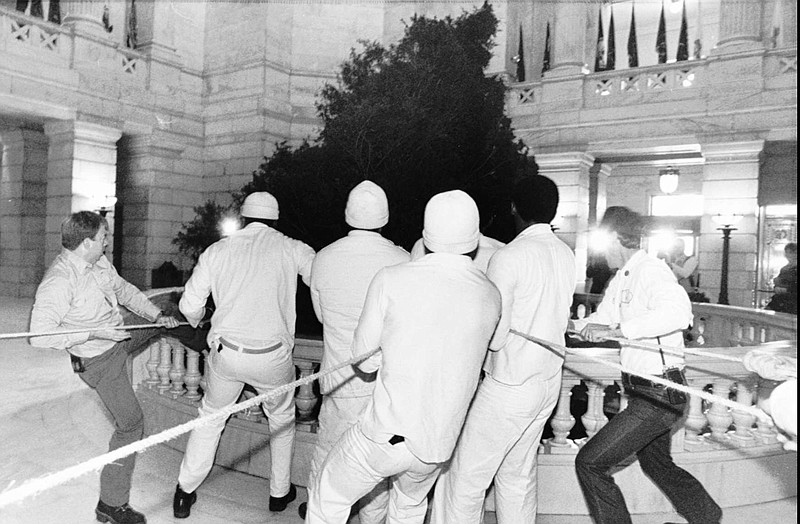 Workers struggle to erect a 30-foot red cedar Christmas tree in the rotunda of the Arkansas State Capitol on Dec. 1, 1987. (AP file photo/Danny Johnston)