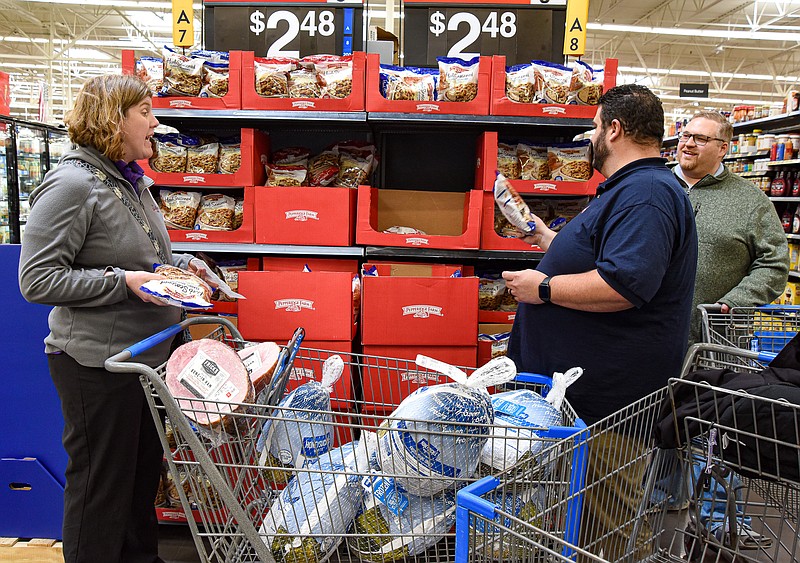 Julie Smith/News Tribune photo: 
While Justin Windell, at right, listens, Sarah Windell, left, and Brian Vogeler discuss which flavor of stuffing and how much to get while shopping Thursday, Nov. 17, 2022, at Walmart in Jefferson City. The Windells are majors at The Salvation Army  of Jefferson City while Vogeler serves as director of the Center of Hope. They were on a mission to purchase items for the shelter's  Thanksgiving meal Thursday. Vogeler secured financing for the meal so the trio went shopping for turkey, ham and all the fixings.