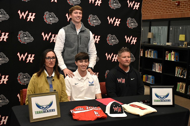 Cade Harp of White Hall, seated center, signed a letter of intent with Arkansas State University Mountain Home on Wednesday at the White Hall High School media center. Seated with him are his mother Courtney, and father and White Hall Coach Shane Harp. Standing is his brother Wes Harp. (Pine Bluff Commercial/I.C. Murrell)