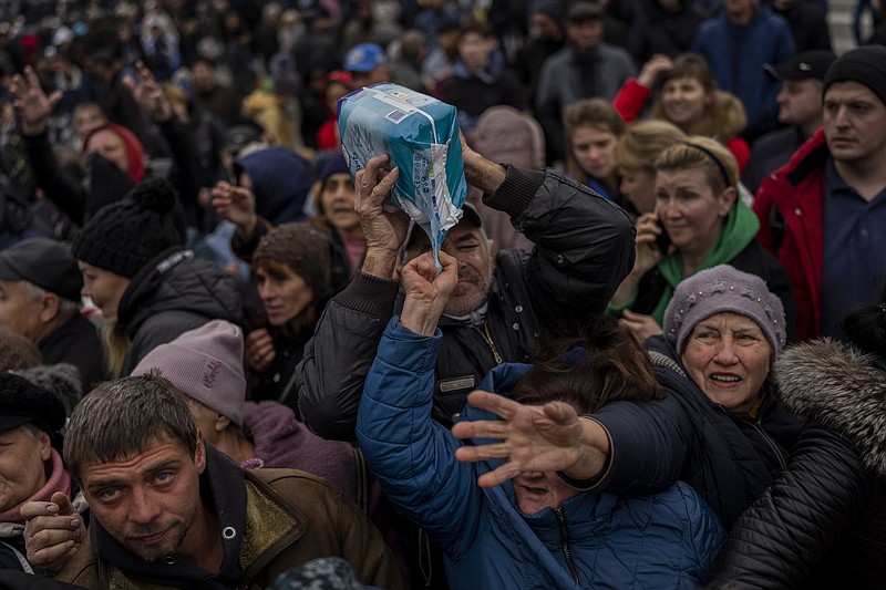 Residents gathering at an aid distribution point receive supplies Friday, Nov. 18, 2022, in downtown Kherson, southern Ukraine. (AP Photo/Bernat Armangue)