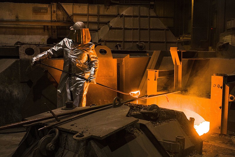 FILE -- An employee in protective clothing takes a sample from the furnace at the steel producer, Salzgitter AG, in Salzgitter, Germany, Thursday, March 22, 2018. Germany’s biggest industrial union has agreed with employers on a pay deal that will see millions of workers get raises totaling 8.5% over two years as well as one-time payments meant to cushion the effect of sky-high inflation. (AP Photo/Markus Schreiber)