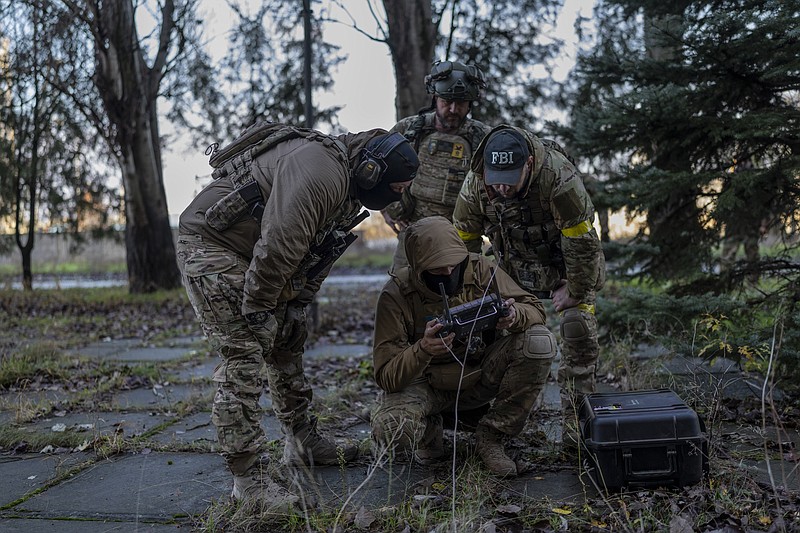 Sniper and commander of a unit in the south, alias Kurt, left, checks real-time drone footage during an operation against Russian positions, Kherson region, southern Ukraine, Saturday, Nov. 19, 2022. (AP Photo/ Bernat Armangue)